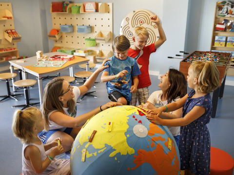 Bambini giocano intorno a un grande mappamondo in una sala giochi luminosa a Valamar Camping Istra, Istria, Croazia.