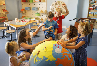 Bambini giocano intorno a un grande mappamondo in una sala giochi luminosa a Valamar Camping Istra, Istria, Croazia.