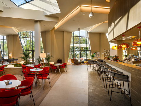 Modernes Café mit roten Stühlen, Bar mit Hockern und großen Fenstern im Valamar Camping Istra, Kroatien.