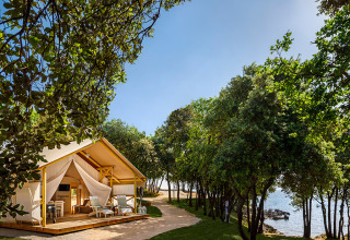 Glamping tent near the sea, shaded by trees, at Valamar Camping Istra holiday park in Istria, Croatia.