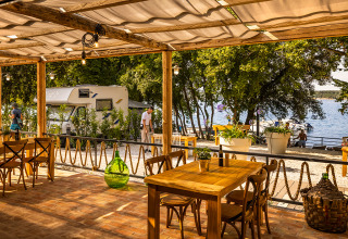 Udendørs restaurant med træmøbler og udsigt over campingvogne og havet i Valamar Camping Istra, Istrien.