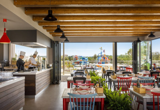Modern restaurant with open kitchen and view of colorful water playground at Valamar Camping Istra, Istria, Croatia.