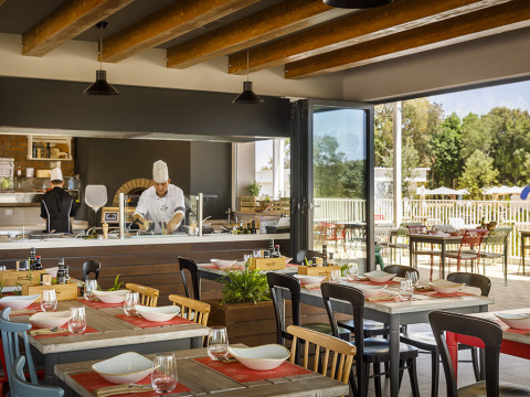 Restaurant intérieur au Valamar Camping Istra, Istrie, Croatie, avec chefs en cuisine ouverte et tables dressées.