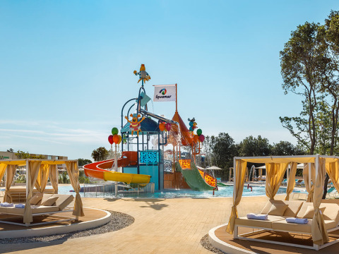 Waterspeeltuin en kleurrijke glijbanen bij Valamar Camping Istra met luxe ligbedden, Istrië, Kroatië.