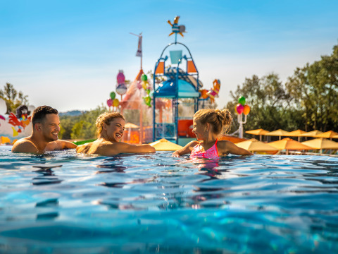 Familie nyder poolen ved Valamar Camping Istra feriepark i Istrien, Kroatien, med vandlegeplads i baggrunden.