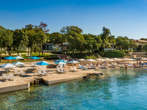 Beachfront at Valamar Camping Istra, Croatia, with sun loungers, umbrellas, and clear blue water.