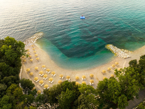 Luftaufnahme eines Strandes mit Sonnenschirmen und klarem Wasser bei Valamar Camping Istra, Istrien, Kroatien.