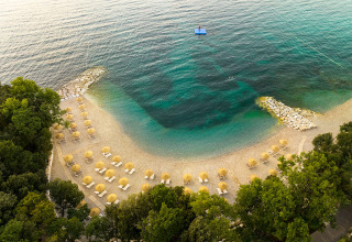 Aerial view of a serene beach with umbrellas and clear blue water at Valamar Camping Istra, Istria, Croatia.