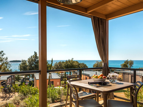 Vista desde la Bella Vista Chalet en Valamar Camping Istra, Croacia, con terraza, mar y mesa de comedor.