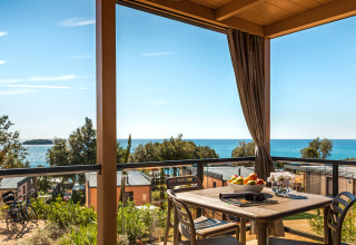 Vista desde la Bella Vista Chalet en Valamar Camping Istra, Croacia, con terraza, mar y mesa de comedor.