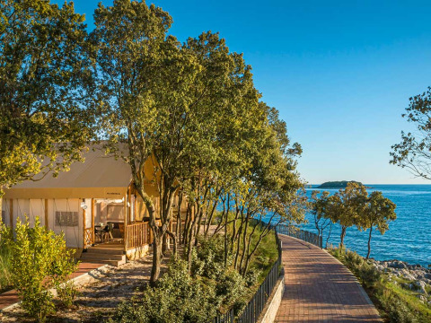 Safaritent bij Sunset Premium Glamping Tent, Valamar Camping Istra in Kroatië, met zeezicht en bomen.