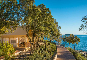 Tienda safari en Sunset Premium Glamping Tent, Valamar Camping Istra, Croacia, con vista al mar y árboles.