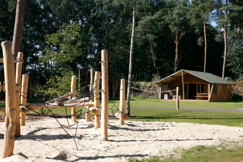 Tienda Safari Lodge Deluxe y área de juegos arenosa en Familievakantiepark Krieghuusbelten, Países Bajos.