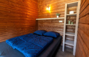 Interior view of the wooden Safarilodge deluxe tent with bed and shelf at Krieghuusbelten, Netherlands.