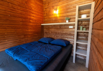 Interior view of the wooden Safarilodge deluxe tent with bed and shelf at Krieghuusbelten, Netherlands.