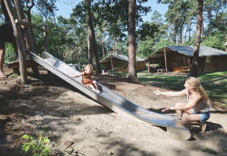 Une mère attend son enfant qui descend un toboggan près de tentes safari à Familievakantiepark Krieghuusbelten, Pays-Bas.