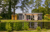 Feriehus ved søen i Holiday Park De Lochemse Berg, omgivet af træer og natur i Gelderland, Holland.