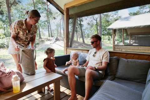 Famille sur la terrasse d’une tente Safarilodge deluxe au Familievakantiepark Krieghuusbelten, Pays-Bas.