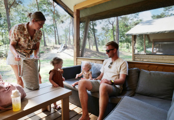 Family enjoying time at a Safarilodge deluxe tent at Familievakantiepark Krieghuusbelten, Netherlands.