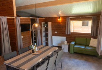 Interno della Safarilodge deluxe al Familievakantiepark Krieghuusbelten con tavolo da pranzo e divano.