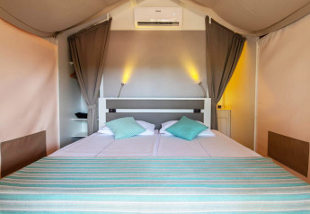 Indretning af soveværelse i Mini Lodge safari-telt på Camping Arena One 99 Glamping i Kroatien.