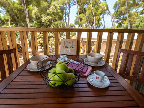 Ontbijttafel op terras met groene appels, koffie en kommen bij Mini Lodge, Arena One 99 Glamping, Kroatië.