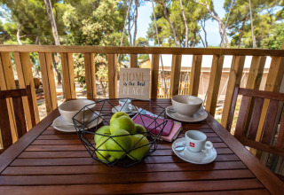 Tavolo da colazione all'aperto con mele verdi, caffè e ciotole su terrazza in legno al Mini Lodge, Arena One 99 Glamping, Croazia.