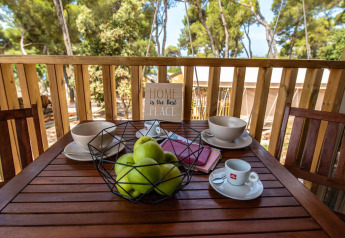 Tavolo da colazione all'aperto con mele verdi, caffè e ciotole su terrazza in legno al Mini Lodge, Arena One 99 Glamping, Croazia.