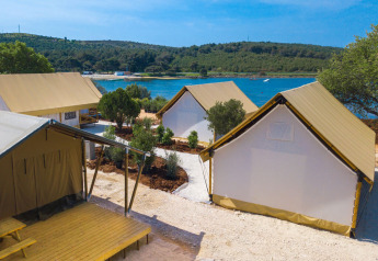 Twee slaapkamer safaritenten bij Camping Arena One 99 Glamping in Kroatië, met uitzicht op water en natuur.