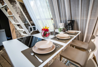 Moderne Küche mit Esstheke, vier Gedecken, Kaffeemaschine, Tassen und Blumen in einem Safarizelt.