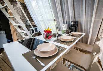 Cucina moderna con bancone, quattro coperti, macchina del caffè, tazze e fiori in una tenda safari.