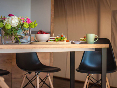 Tafel in een safaritent bij Camping Arena One 99 Glamping in Kroatië met bloemen, sandwiches en koffie.