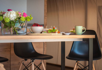 Table dans une tente safari au Camping Arena One 99 Glamping en Croatie avec fleurs, sandwichs et café.