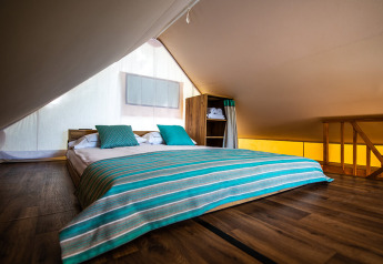Premium to-sengs safari loft telt interiør med lavt loft og dobbeltseng, Camping Arena One 99 Glamping, Kroatien.