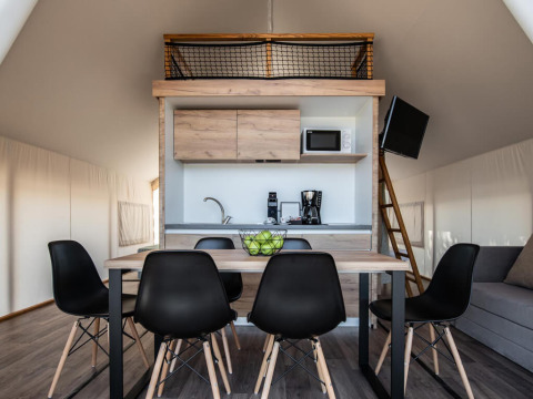 Interior de tienda safari premium en Camping Arena One 99 Glamping, Croacia, con cocina y comedor moderno.