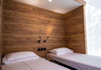 Twee enkele bedden met wit linnengoed en houten panelen in een premium safaritent op Camping Arena One 99.