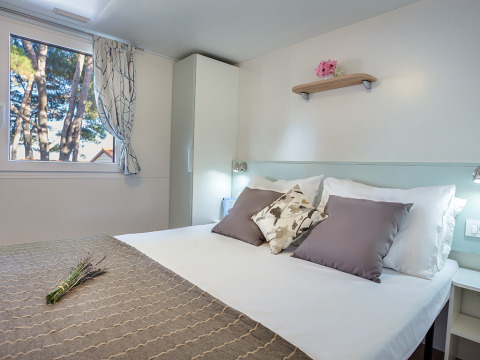 Bedroom inside Ježevac Home at Valamar Camping Ježevac, Croatia, featuring a cozy double bed and modern decor.