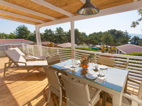 Sunny terrace with dining table and loungers at Ježevac Home, Valamar Camping Ježevac, Croatia.