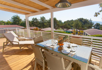 Terrazza soleggiata con tavolo da pranzo e lettini a Ježevac Home, Valamar Camping Ježevac, Croazia.