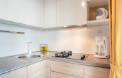 Coin cuisine moderne dans un lodge avec plaque gaz, cafetière, bouilloire électrique et fruits frais sur le plan.