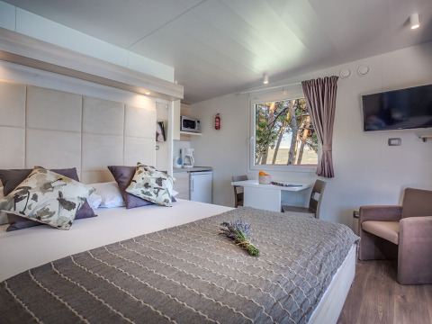 Moderne lodgeværelse på Lungomare Chalet med havudsigt, dobbeltseng, sofa, spiseplads og tekøkken.