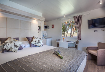 Moderne lodgeværelse på Lungomare Chalet med havudsigt, dobbeltseng, sofa, spiseplads og tekøkken.