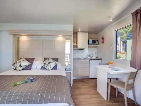 Moderne lodge med dobbeltseng, tekøkken, spisebord og vindue med havudsigt på Valamar Camping Ježevac.