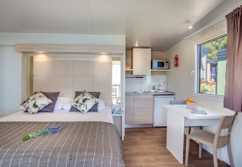 Moderne lodge med dobbeltseng, tekøkken, spisebord og vindue med havudsigt på Valamar Camping Ježevac.