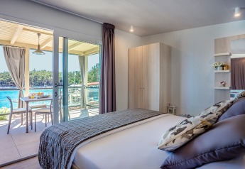 Lyst værelse med dobbeltseng og balkon med udsigt over havet på Lungomare Chalet i Valamar Camping Ježevac.