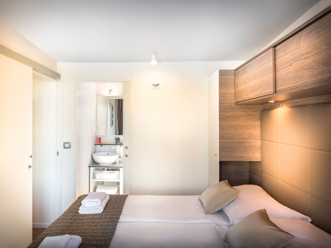 Moderne slaapkamer bij Lungomare Home op Valamar Camping Ježevac in Kroatië, met tweepersoonsbed en badkamer.