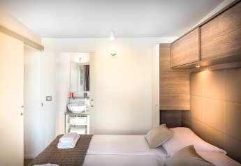 Moderne slaapkamer in Lungomare Home bij Valamar Camping Ježevac, Kroatië, met dubbel bed en badkamer.