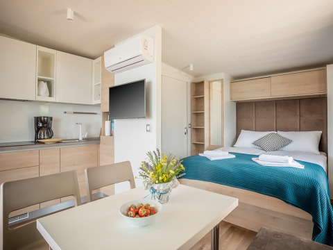 Studio moderne avec cuisine, table à manger, lit double et déco au Lungomare Chalet, Valamar Camping Ježevac, Croatie.