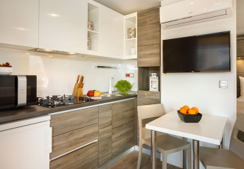 Moderne Küchenzeile mit Holzmöbeln, TV, Esstisch und Obstschale, Lungomare Chalet, Valamar Camping Kroatien.