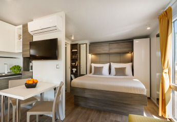 Modernes Lodge-Zimmer mit Doppelbett, Esstisch, Fernseher und Meerblick im Valamar Camping Ježevac Kroatien.
